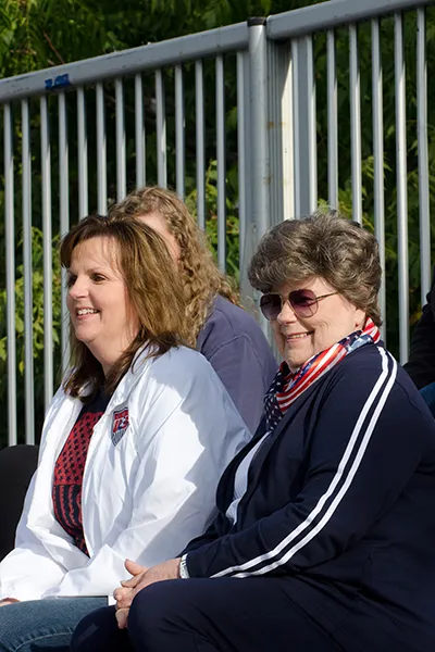 Two women watch a game from the bleachers