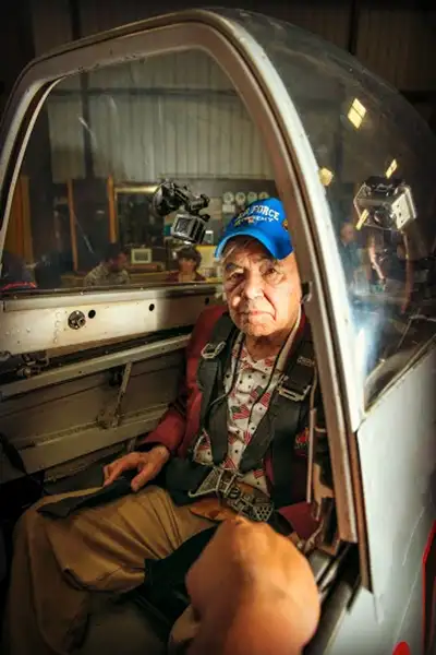 A WWII veteran sits in the cockpit of a vintage airplane