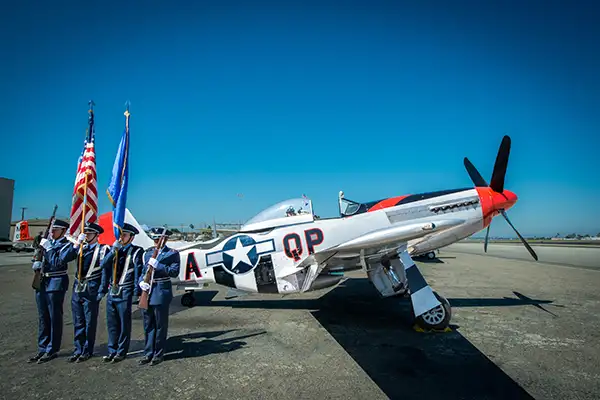 A military guard stands in front of a vintage aircraft