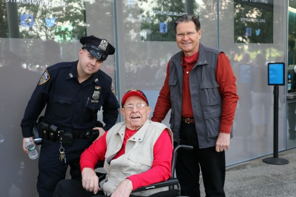 A man in a wheelchair with a New York City police officer and a civilian