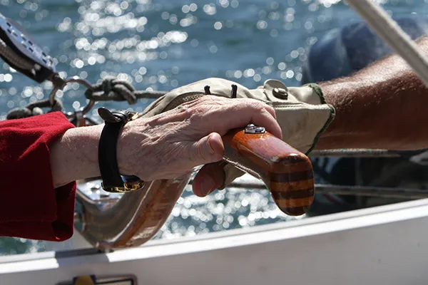 Two hands on the tiller of a sailboat