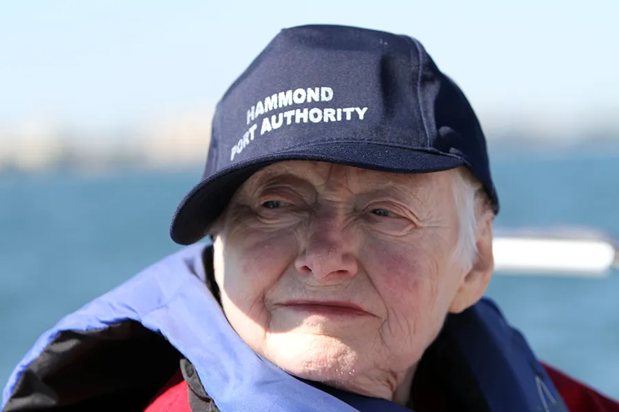 An older woman wearing a baseball cap with a thoughtful expression on her face