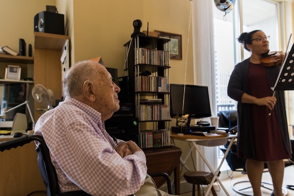 An older man watches a woman play violin