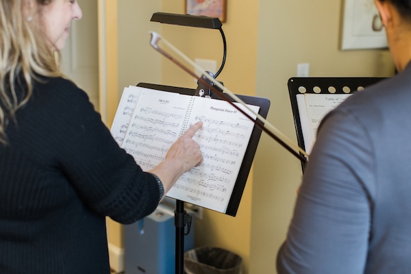 A woman points to notes on a piece of sheet music