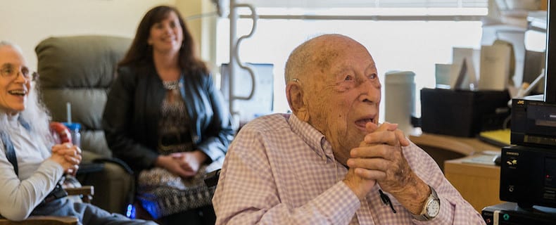 An older man clasps his hands as he listens to live classical music