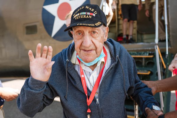 WW2 Veteran Ignacio waves at the camera in front of historic B-24 airplane
