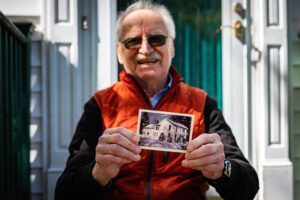 Wish recipient Earl holds a picture of his childhome home while sitting on steps