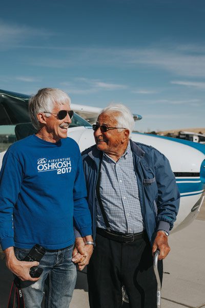 Heinz and his son hold hands and smile broadly after their airplane ride