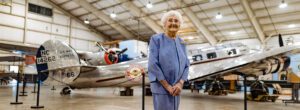 Wish recipient Anne stands in front of Lockheed Electra airplane