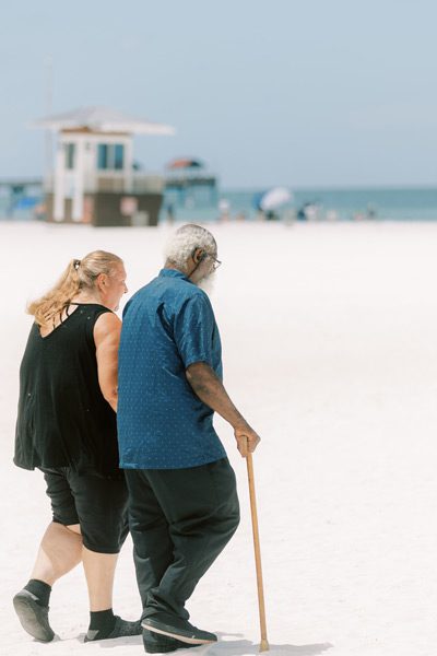 Wish recipient Ken and wife Elizabeth hold hands walking on beach
