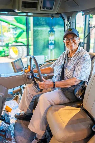 A woman sits in the driver’s seat of a construction truck.