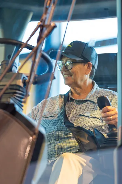 An older woman drives a construction vehicle.