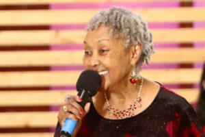 Wish recipient Helen smiling as she sings into microphone