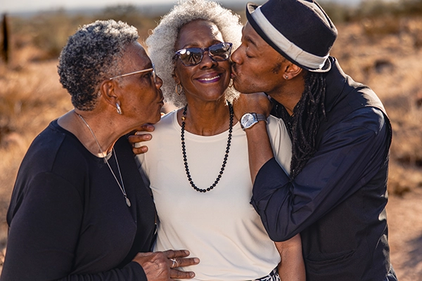 An older African-American woman is embraced by family