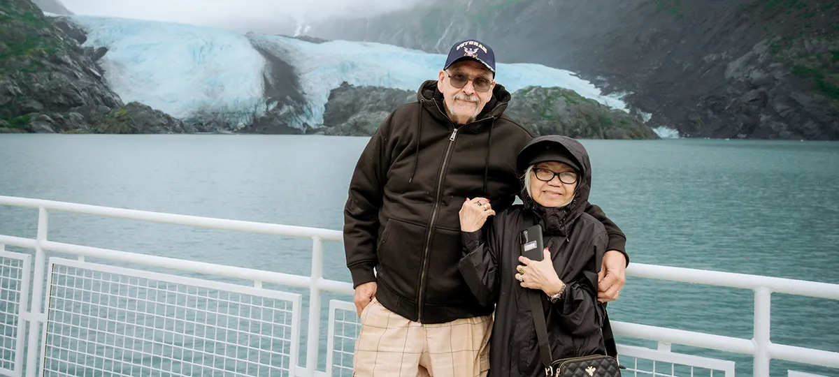 An older couple stands on the deck of a boat tour in Alaska.