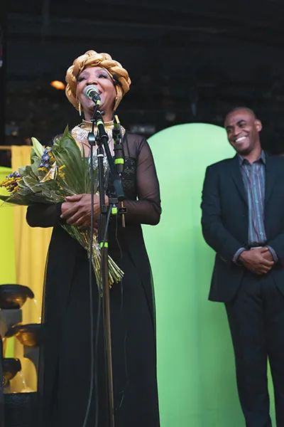 A woman holds flowers while speaking into a microphone.