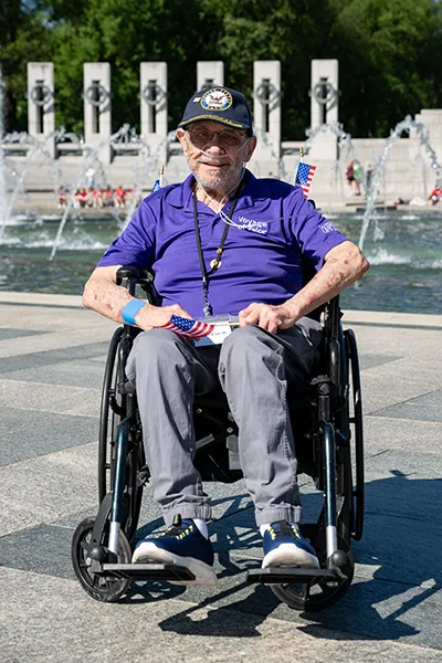 A man in a wheelchair holding an American flag visits Washington, D.C.