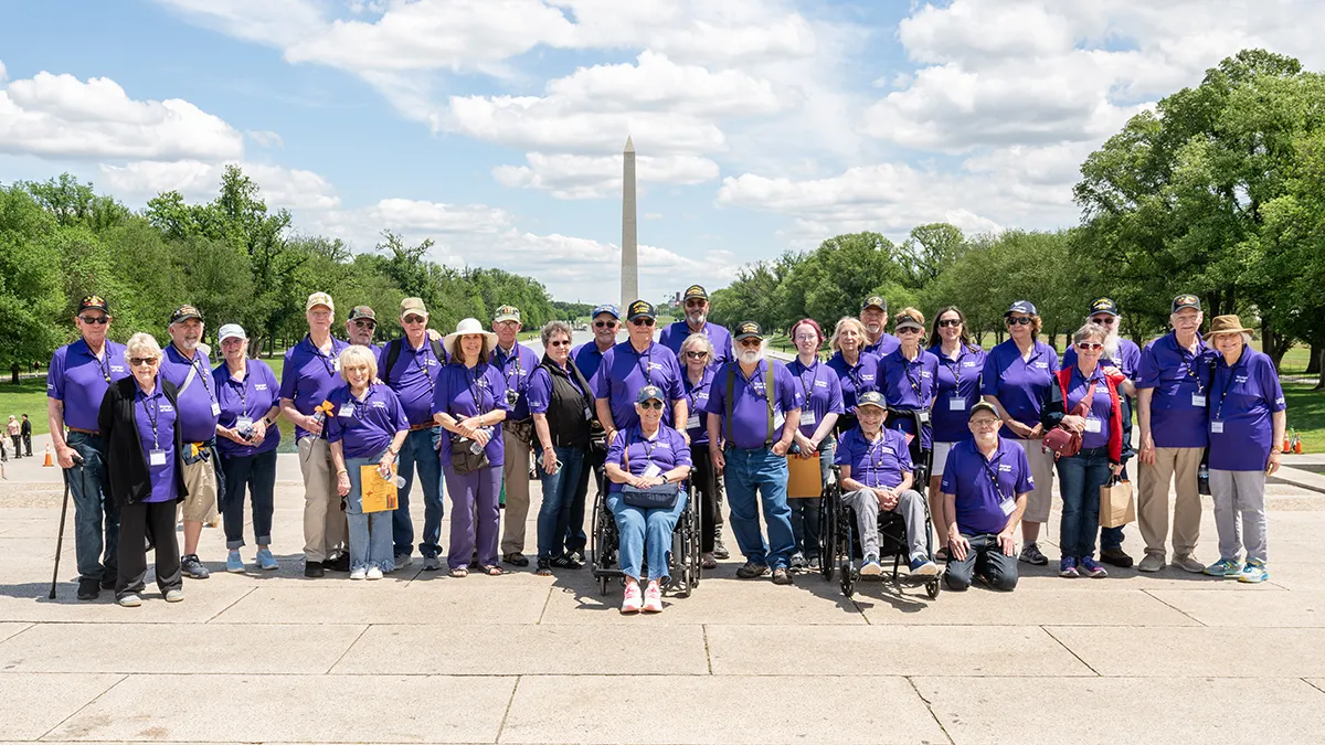 A group of older adults stand in front of the Washington Monument.