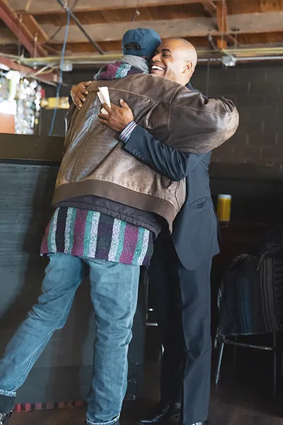 Two men hug one another.