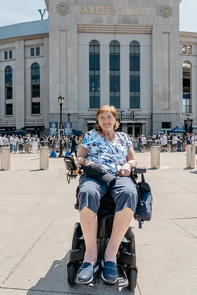 A woman in a wheelchair sits outside Yankee Stadium.