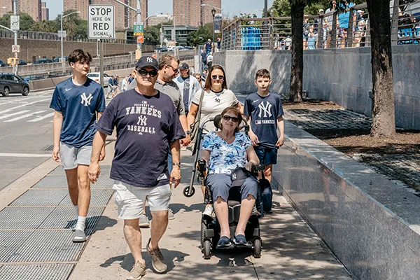 A family wearing New York Yankees gear walks along a city street.