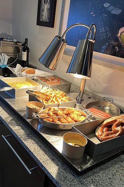 Traditional ballpark food sits on a counter under a warmer.