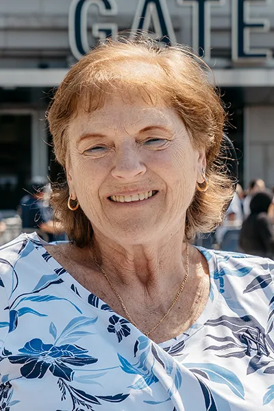 An older woman smiles outside a baseball stadium.