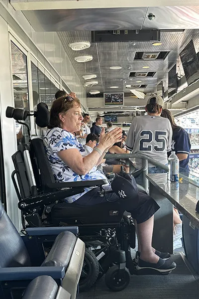 A woman in a wheelchair sits in box seats at a baseball game.
