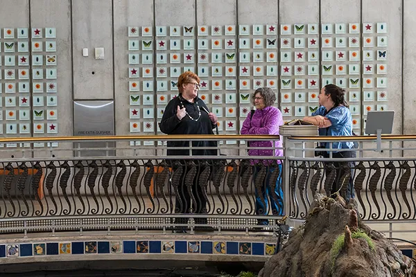 Women stand on a balcony of a museum in front of an art installation.