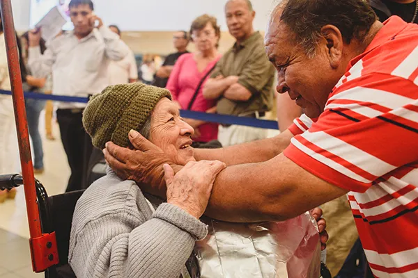 A man looks into an older woman's eyes as he holds her face sweetly