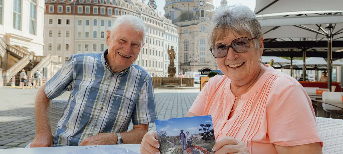 An older man and woman smile while looking at photographs.
