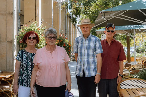 Four senior adults stand together on a restaurant patio.
