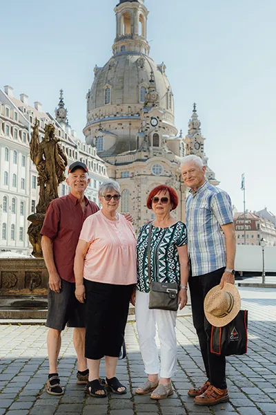 Four senior adults stand in front of historic architecture in Germany.