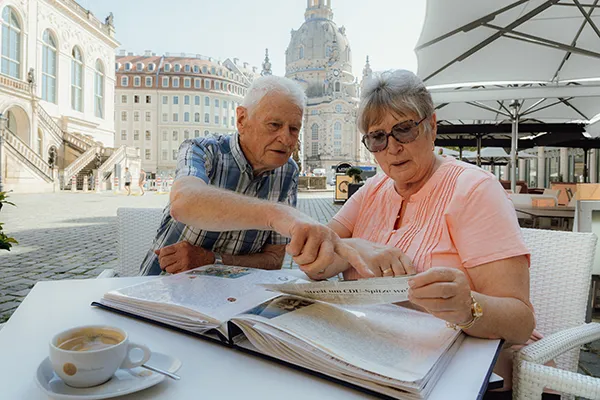 An older man and woman look at a scrapbook together.