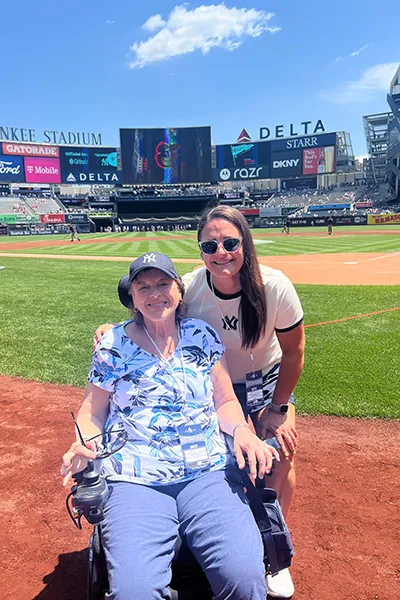 Two women smile from a baseball field.