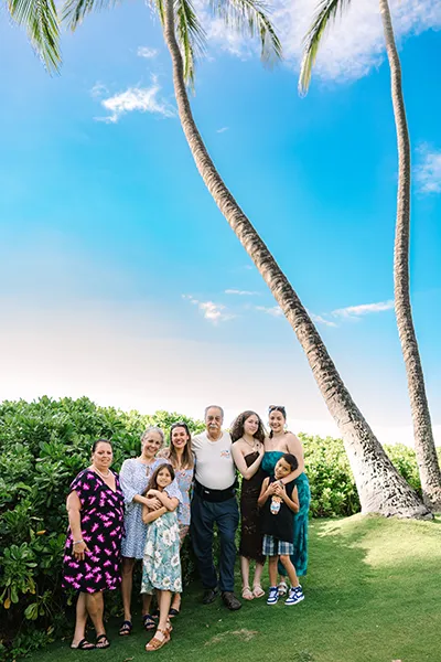 A family stands in front of palm trees.
