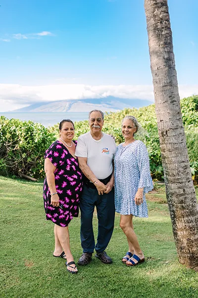 An older man stands outdoors with two older women.