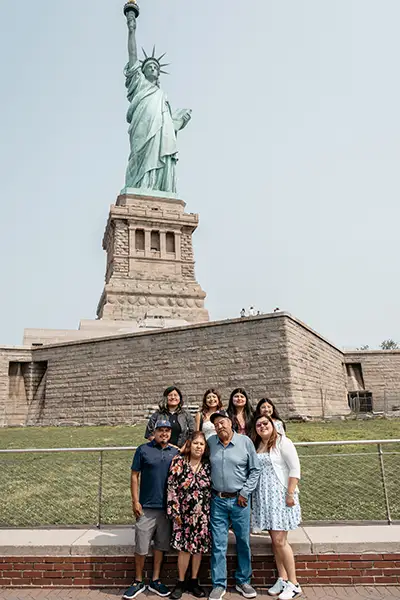 A family stands together at the base of the Statue of Liberty.