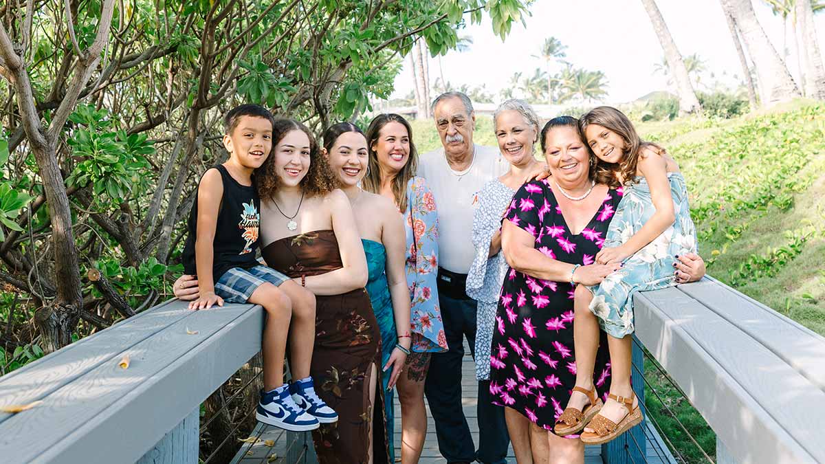 Three generations of a hispanic family stand together on a bridge.