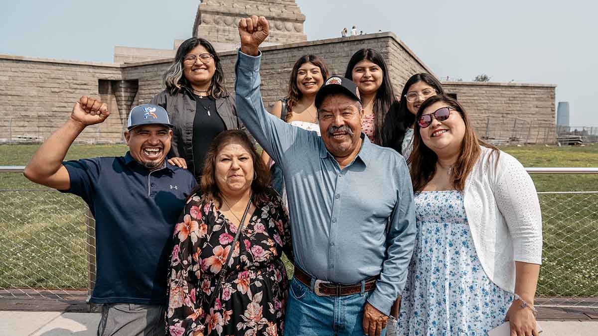 A Mexican family cheers while standing in front of the Statue of Liberty.