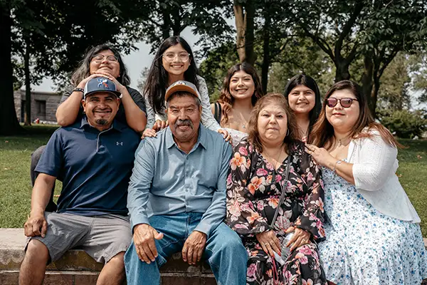 Three generations of a Mexican family sit together in a park.