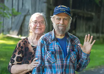 An older couple stands in front of a covered bridge in the Great Smoky Mountains
