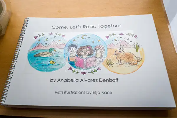 A spiral-bound book in Braille with illustrations sits on a table