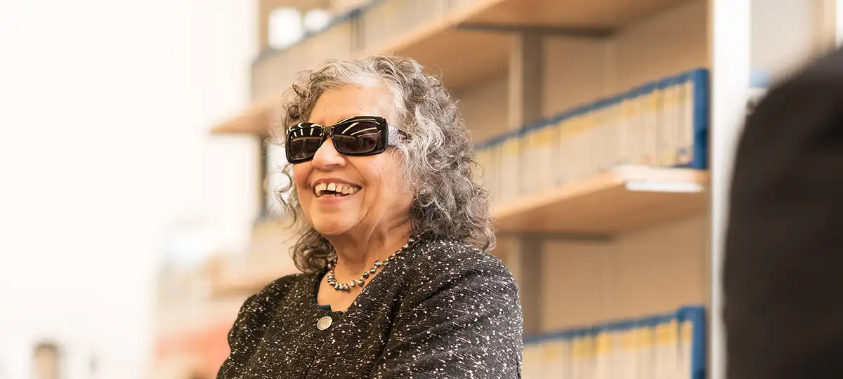 A woman wearing dark glasses laughs in a library