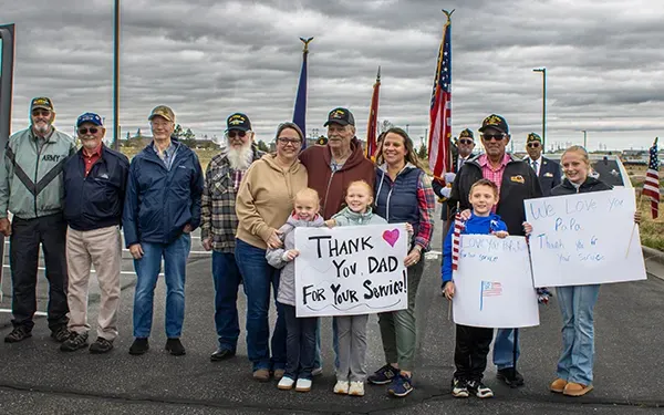 Families hold up signs to honor veterans