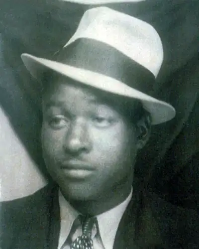 A Black man wears a hat and a suit in a vintage photo