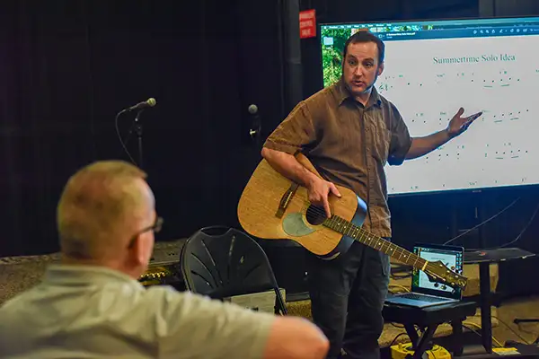 A man with a guitar teaches a private music lesson.