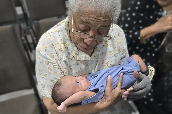 An older African American woman holds a baby