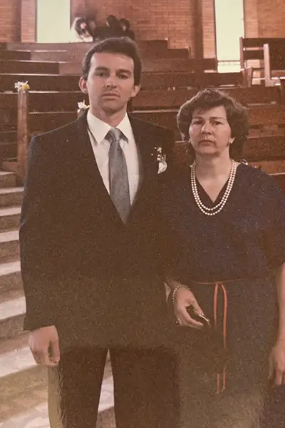 A mother stands with her young adult son in dress clothes inside a church.