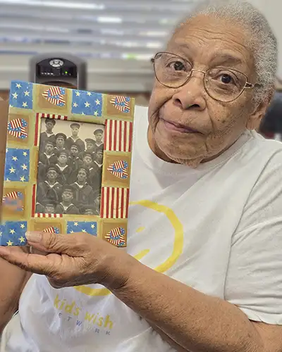 An older woman holds a vintage photograph of World War II Navy sailors